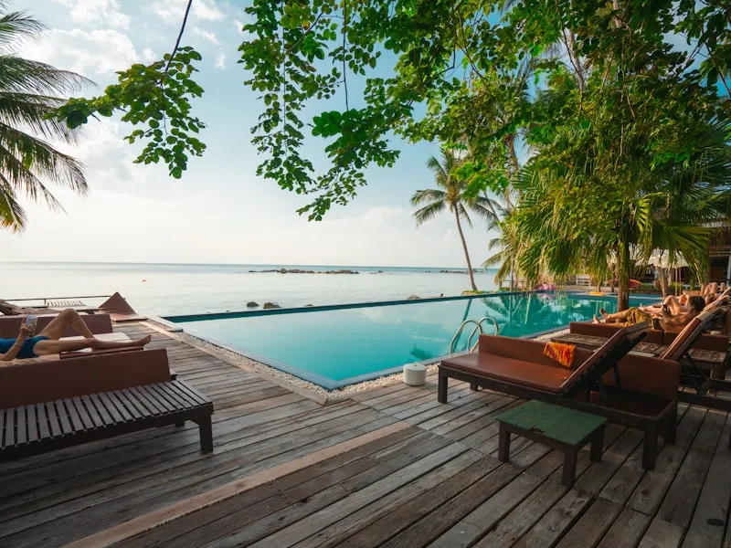 Beachfront infinity pool framed by palms on a wooden deck in the Maldives