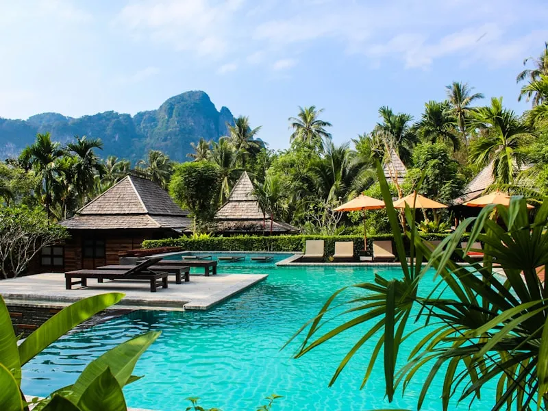 Thatched pavilions and a lagoon pool beneath limestone cliffs in Krabi